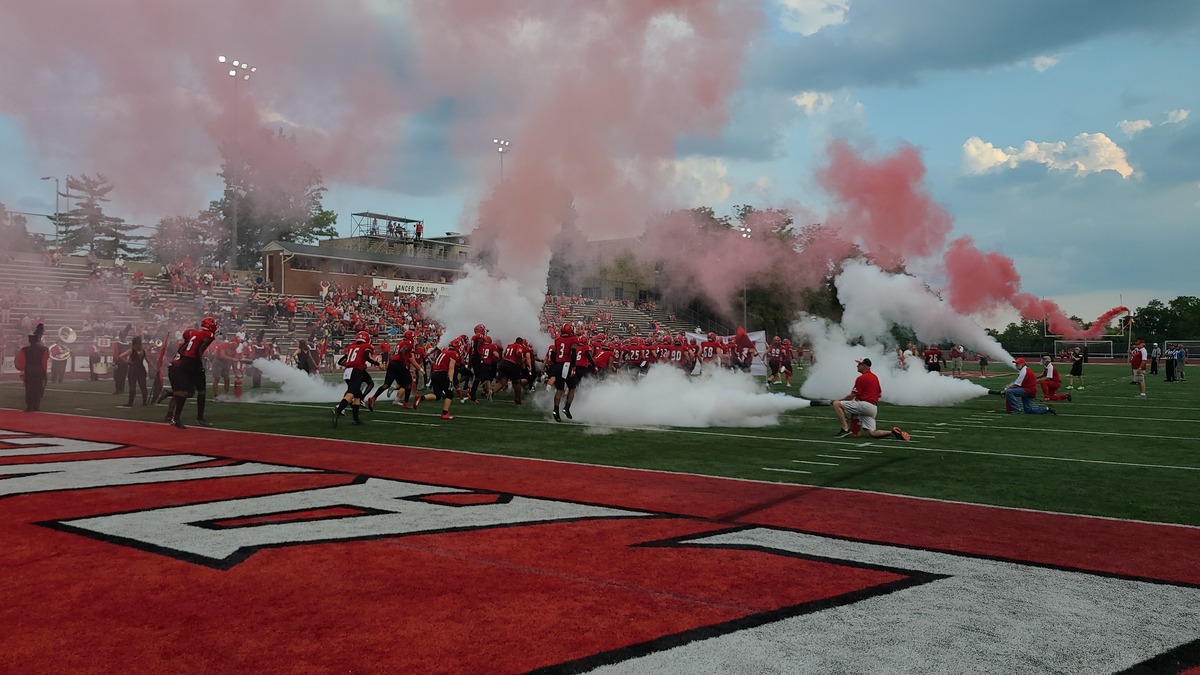 Football players walk through smoke on the field